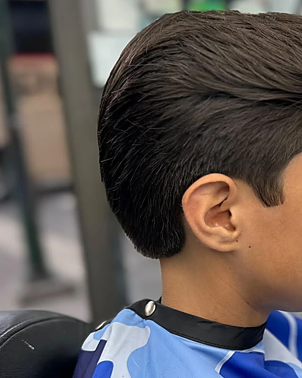 Corte de cabello peinado hacia atrás con volumen arriba, visto de perfil desde la oreja