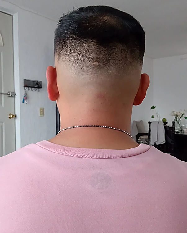 Nuca con degradado bajo y línea limpia, cabello corto y oscuro arriba
