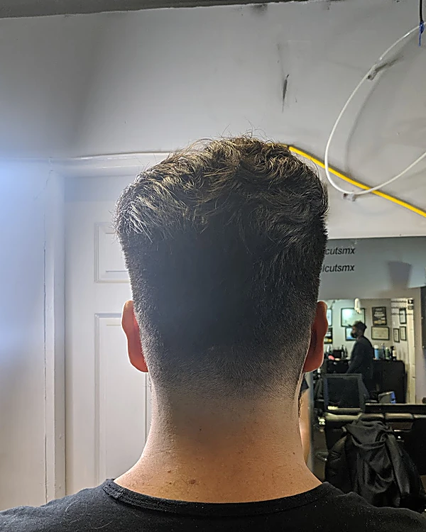 Nuca con degradado medio y cabello texturizado arriba, junto a un aro de luz